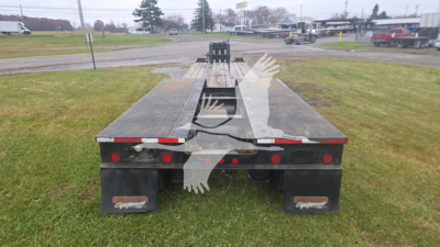 Lowboy trailer with flatbed sections, rear view showing black mud flaps and red brake lights, used condition.
