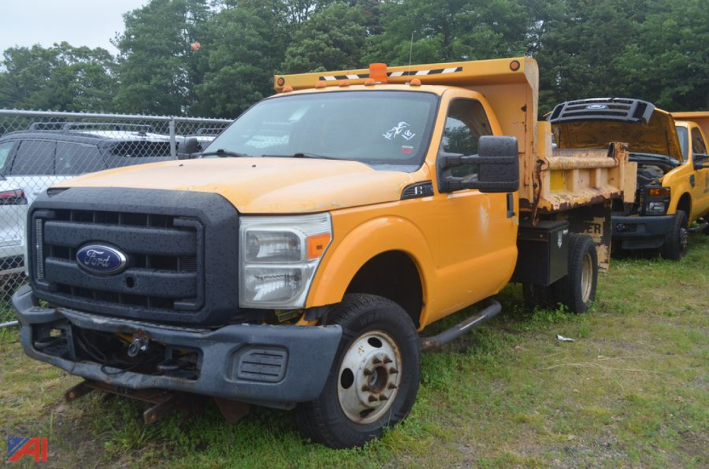 Ford F-350 Super Duty dump truck with orange cab and dump bed, front view in a yard.