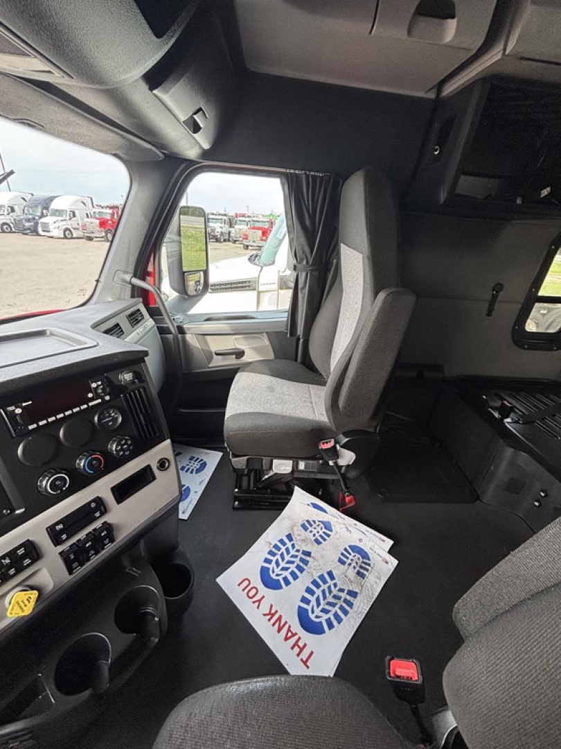 Freightliner Cascadia interior dashboard and driver seat area with steering wheel and controls visible.