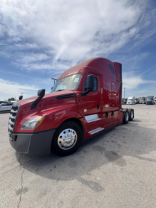 Red Freightliner Cascadia 126 truck in a lot, front three-quarter view, with sleeper cab and chrome wheels.