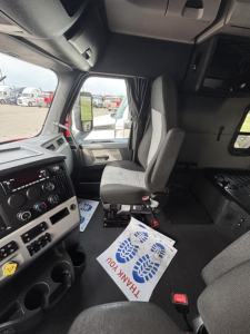 Freightliner Cascadia interior dashboard and driver seat area with steering wheel and controls visible.