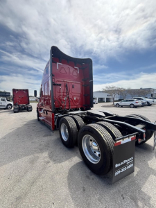 Freightliner Cascadia 126 tractor rear view showing dual rear axles, red cab, and trailer hitch in a truck lot.