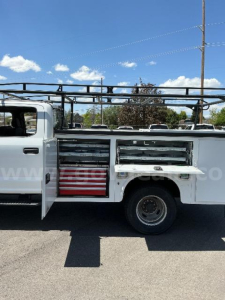 Ford F-Series utility/service truck side view showing storage compartments and ladder rack above. Side drawers and tool compartments with metal handles.