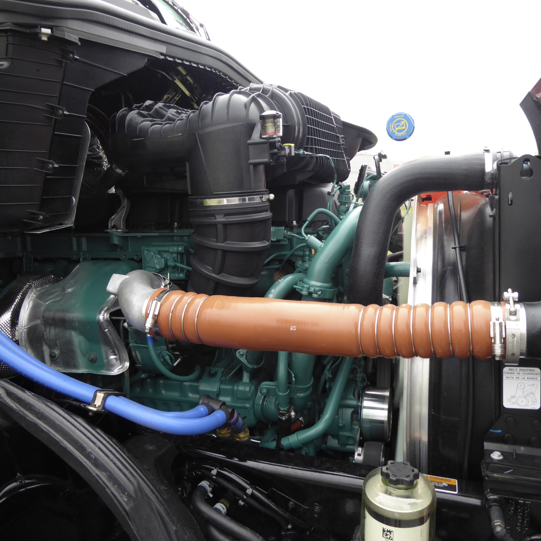 Volvo VNL64T860 engine bay showing orange insulated turbo hose and green engine components with surrounding hoses and radiator area.