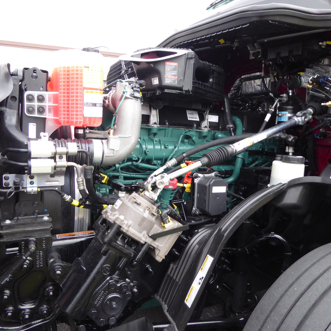 Volvo VNL64T860 engine bay showing green engine block, red air filter housing, hoses, wiring, and belts.
