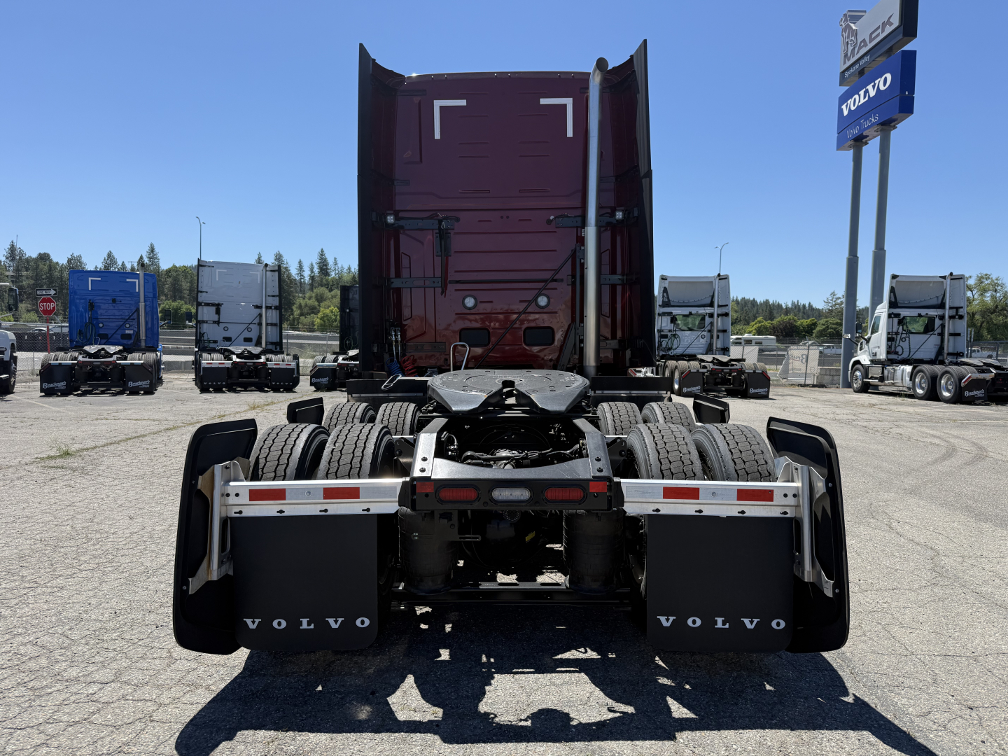 Tractor rear view showing fifth wheel and dual rear axles on a new 2026 Volvo VNL64T860 sleeper cab. Visible Volvo mud flaps and dealership lot in background.