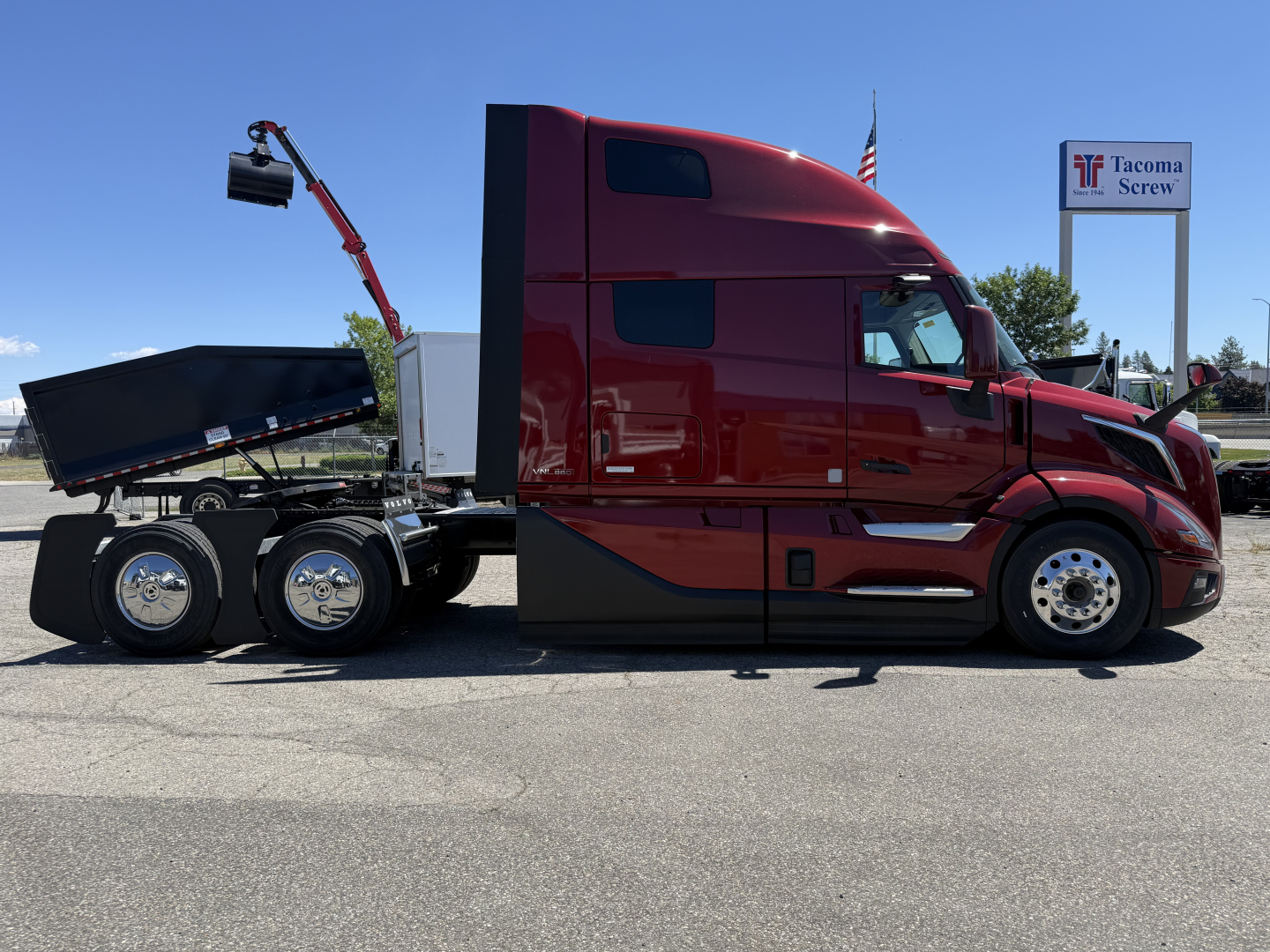 Volvo VNL64T860 tractor-trailer side view showing red cab and black dump bed attached to rear wheels.
