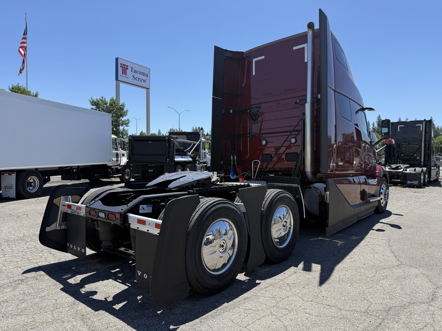 Volvo VNL64T860 tractor-trailer cab in burgundy with sleeper, rear and side view showing dual rear axles and mud flaps.
