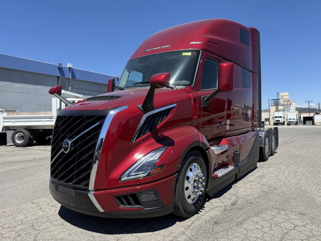 Volvo VNL64T860 sleeper tractor in red, front-right view, showing large grille, aerodynamic mirrors, and chrome wheels.