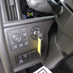 Dashboard area of a Volvo VNL truck showing ignition with key inserted and surrounding control panel with switches and gauges.