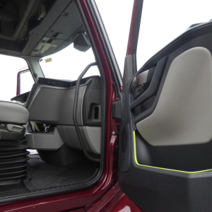 Volvo VNL64T860 cab interior view from open driver door showing steering, dashboard, and door panel with lime-yellow trim.