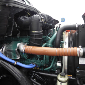 Volvo VNL64T860 engine bay showing orange insulated turbo hose and green engine components with surrounding hoses and radiator area.