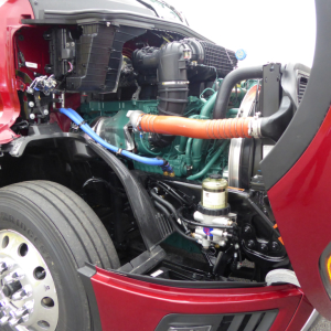 Volvo VNL64T860 engine bay showing diesel engine with green block, orange air intake hose, blue hose, radiator, and front suspension components.