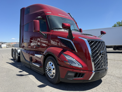 Volvo VNL64T860 truck in red exterior, front-left view showing grille, headlights, aerodynamic mirrors, chrome wheels, and sleeper cab.