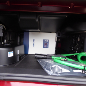 Volvo VNL64T860 cab interior showing a white Xantrex power box and green charging hoses in the storage area.