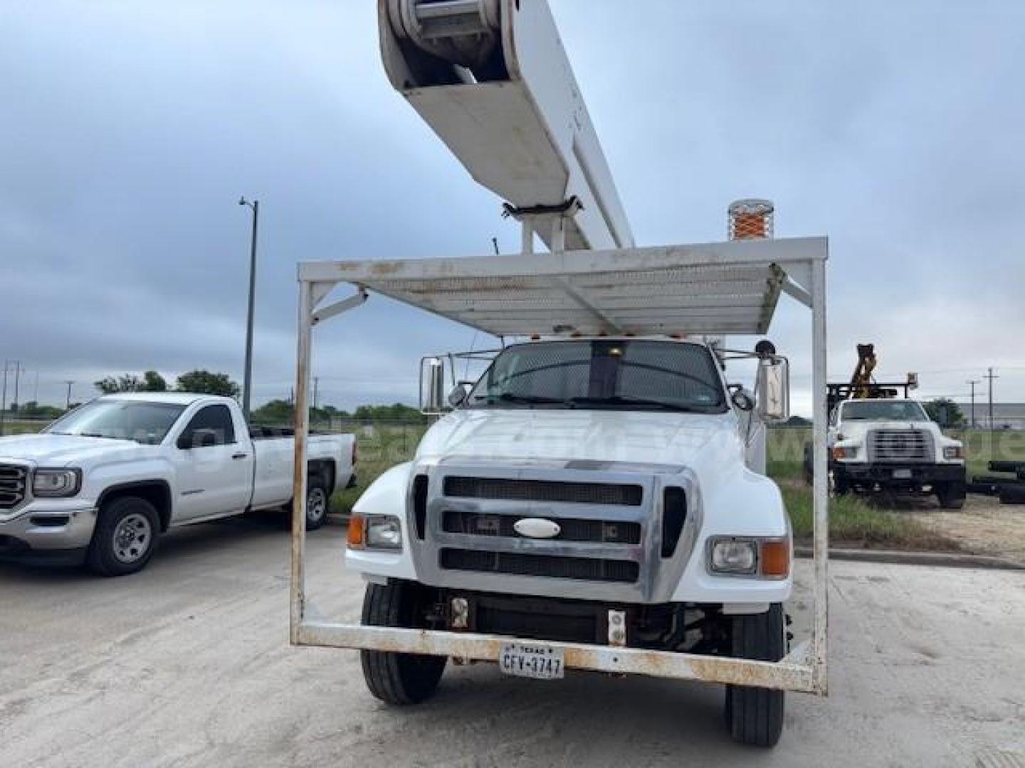 Truck bucket lift mounted on Ford F-750 with front grille and license plate visible.
