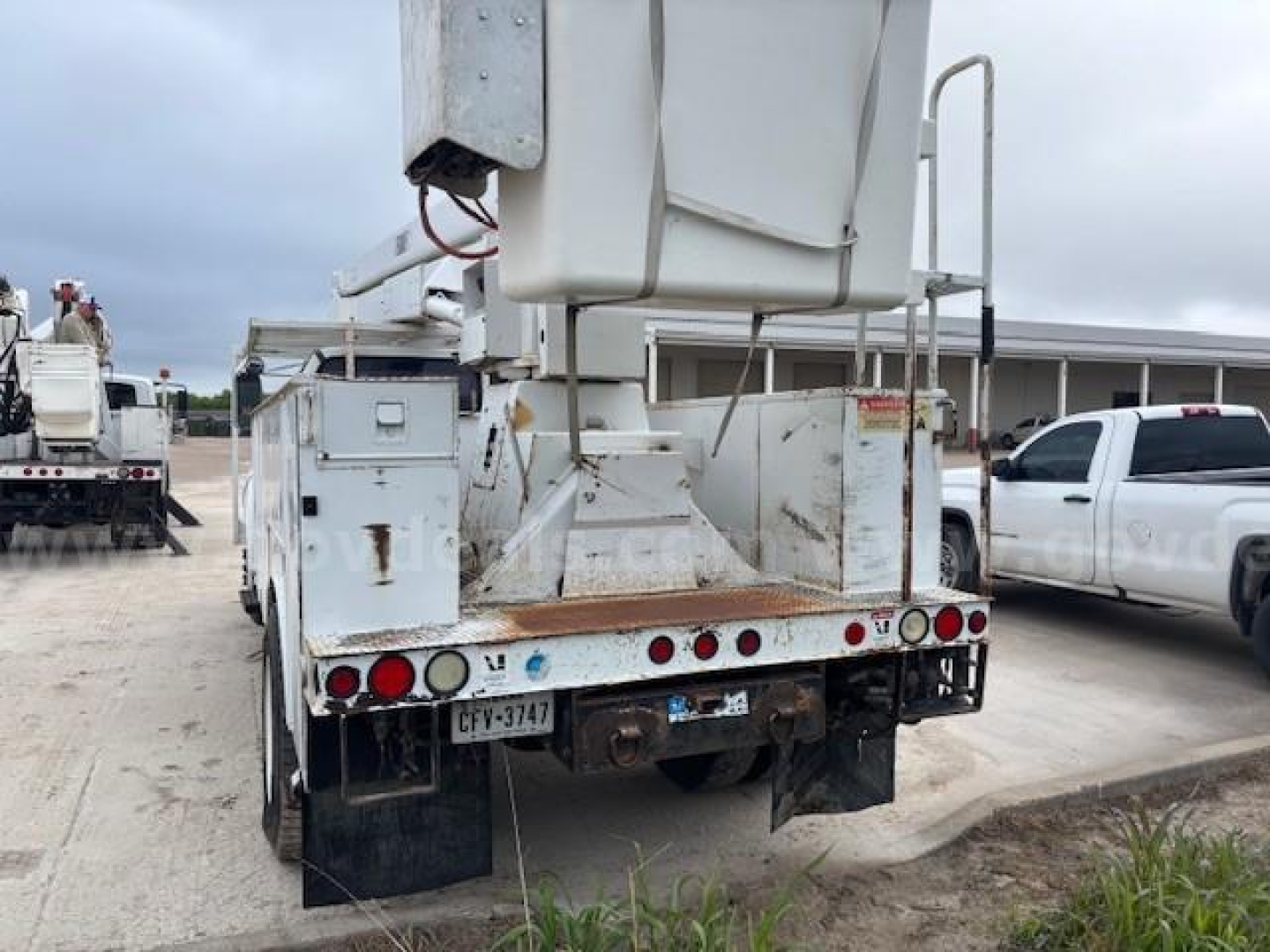 Rear view of a Ford F-750 bucket truck with a hydraulic lift bucket, multiple lights, and rear bumper; license plate visible; utility body and equipment are mounted.