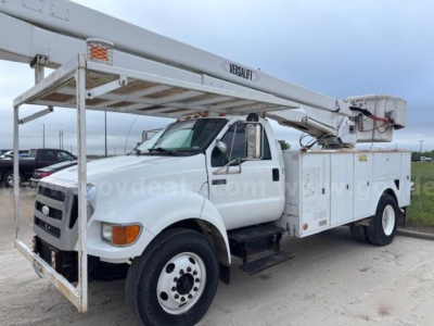 Ford F-750 bucket truck with Versalift aerial lift on white chassis, front three-quarter view showing boom mounted over utility compartments and bucket.