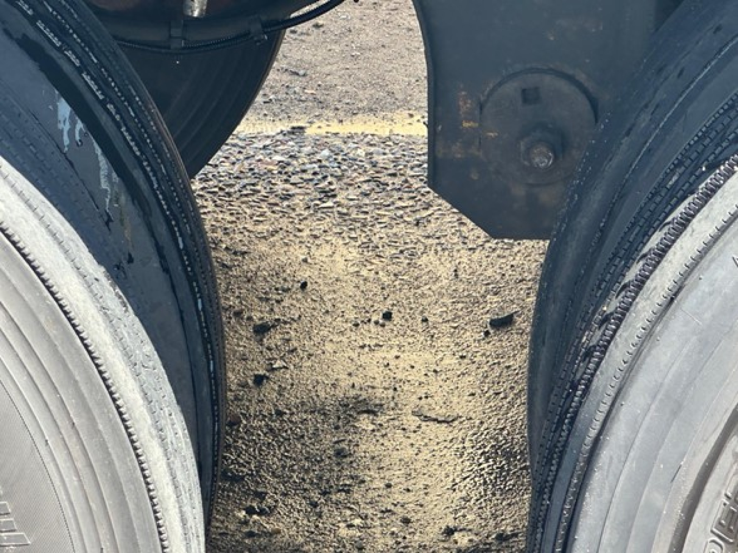 Trailer dual wheels and undercarriage view showing tire treads and mud on ground between axles on a used 2024 Wabash Duraplate dry van trailer.