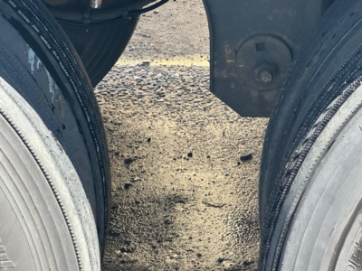 Trailer dual wheels and undercarriage view showing tire treads and mud on ground between axles on a used 2024 Wabash Duraplate dry van trailer.