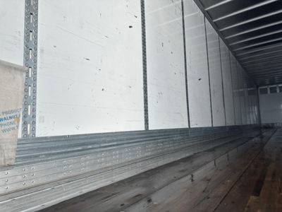 Trailer interior showing metal side walls and floor with tracks and riveted joints.