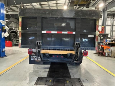 Dump bed of a 2011 International 4300 service truck, rear view showing tailgate, reflective striping, and hydraulic system.