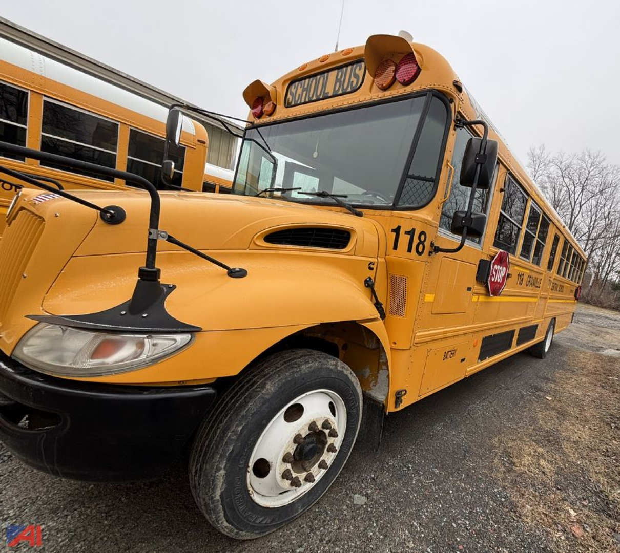 School bus CE Series with wheelchair lift, front-left view, yellow body, bus number 118, stop sign extended, large windshield and mirrors visible.