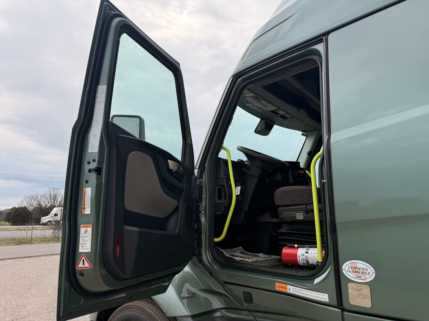 Volvo VNL64T860 cab interior showing open driver door and entry, with yellow handrails and dash area visible.