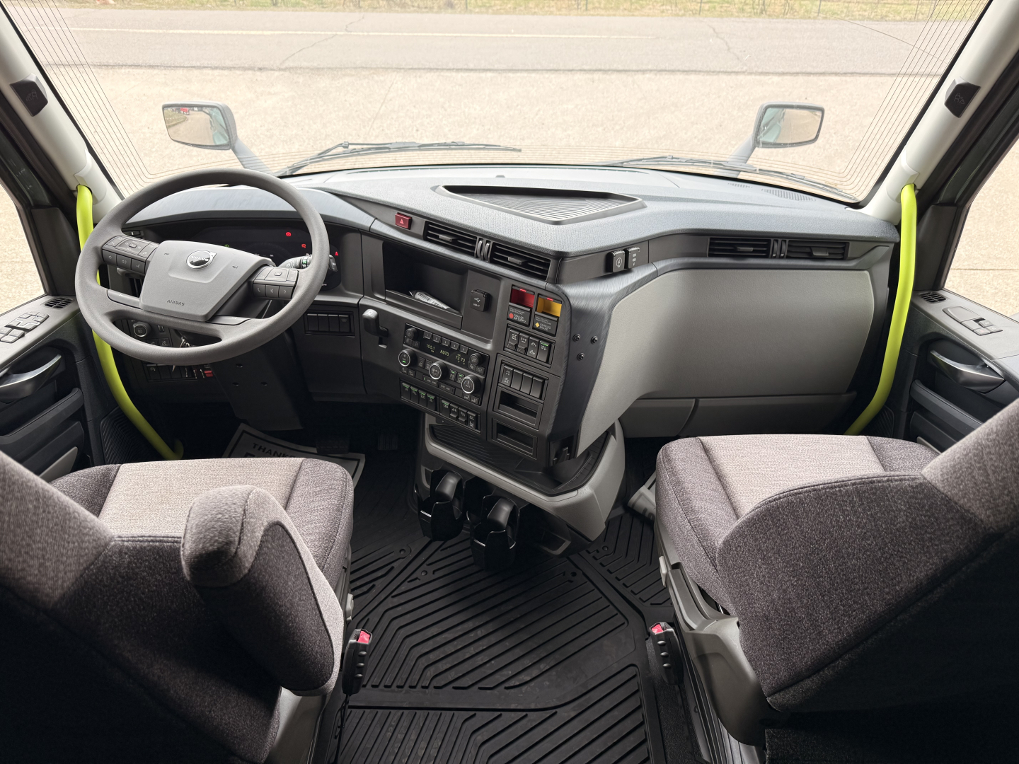 Volvo VNL64T860 truck interior cockpit view showing steering wheel, instrument cluster, center console, and two captain chairs.