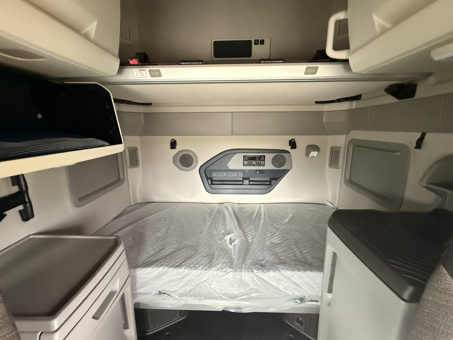Volvo VNL64T860 interior sleeper bay showing overhead cabinets and control panel with bunk area and surrounding storage compartments.