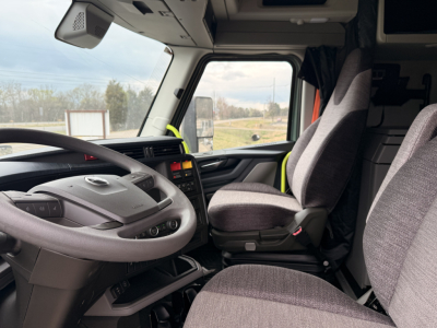 Cab interior of a Volvo VNL64T860 truck showing steering wheel, driver seat, passenger seat, dashboard, and side window.