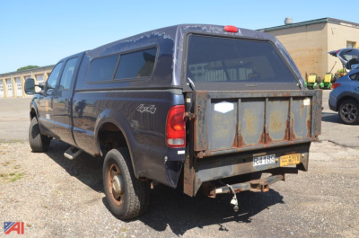 Ford F-350 Super Duty pickup truck with a rusted bed cap and 4x4 badge, rear view showing tailgate, bumper, and dual rear tires.