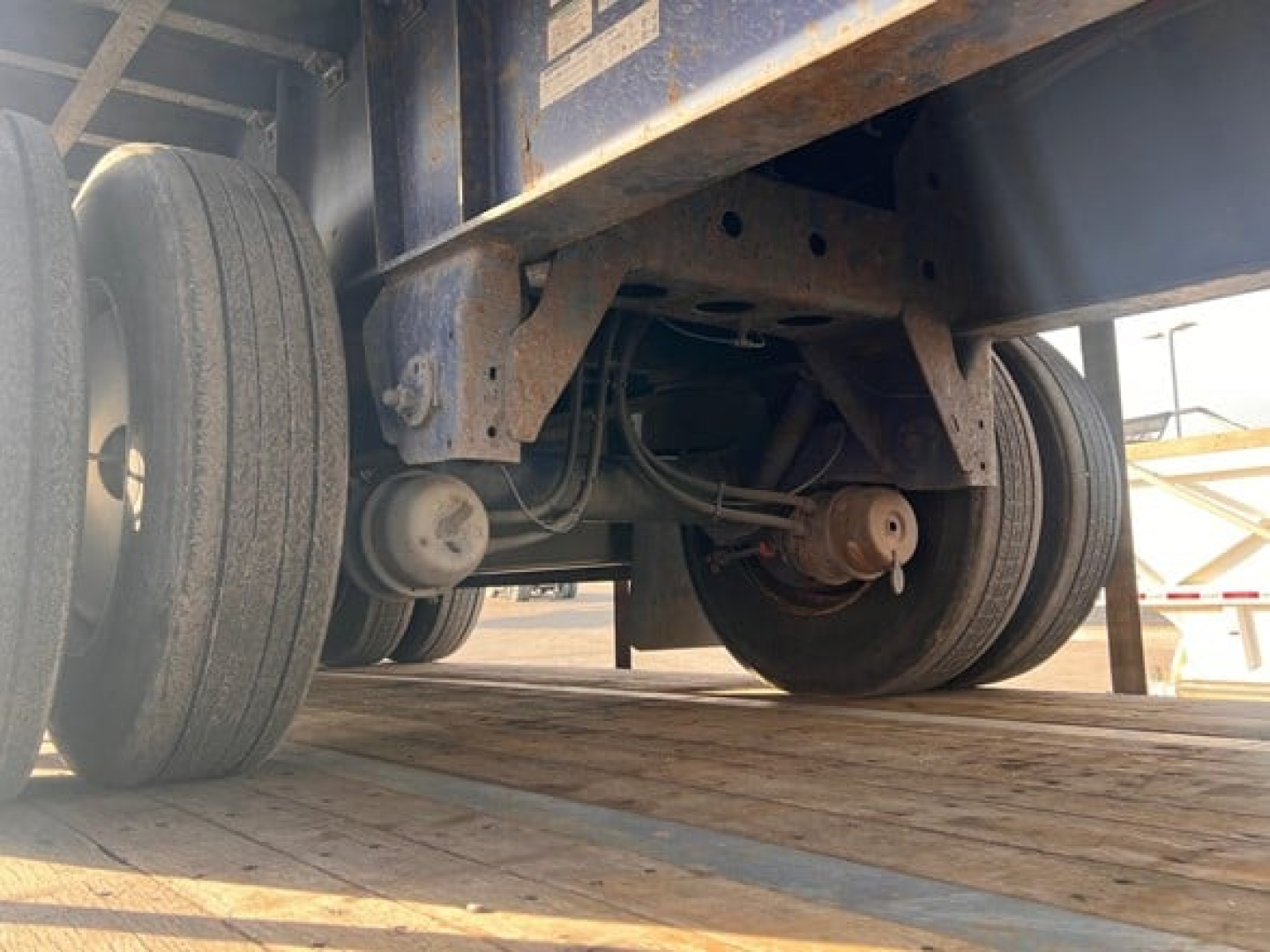 Trailer undercarriage showing dual rear wheels and suspension components.
