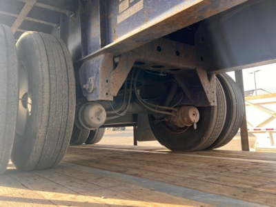Trailer undercarriage showing dual rear wheels and suspension components.
