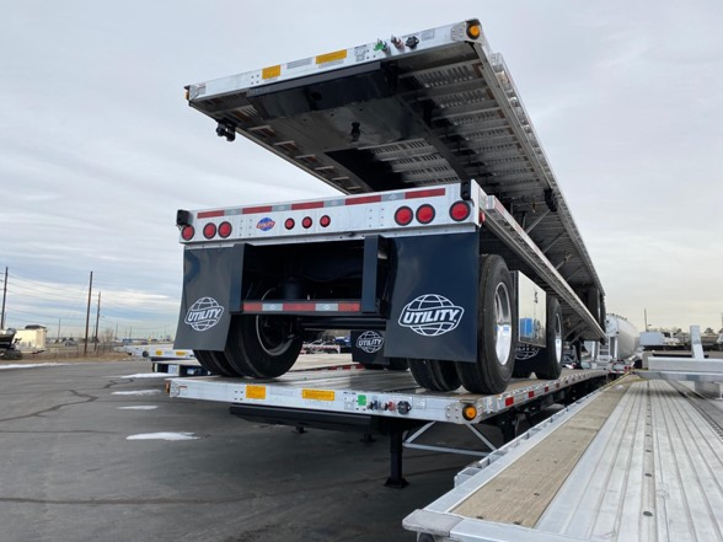 Flatbed trailer showing a raised deck on a Utility 4000Ae with rear axles and loading ramps visible.