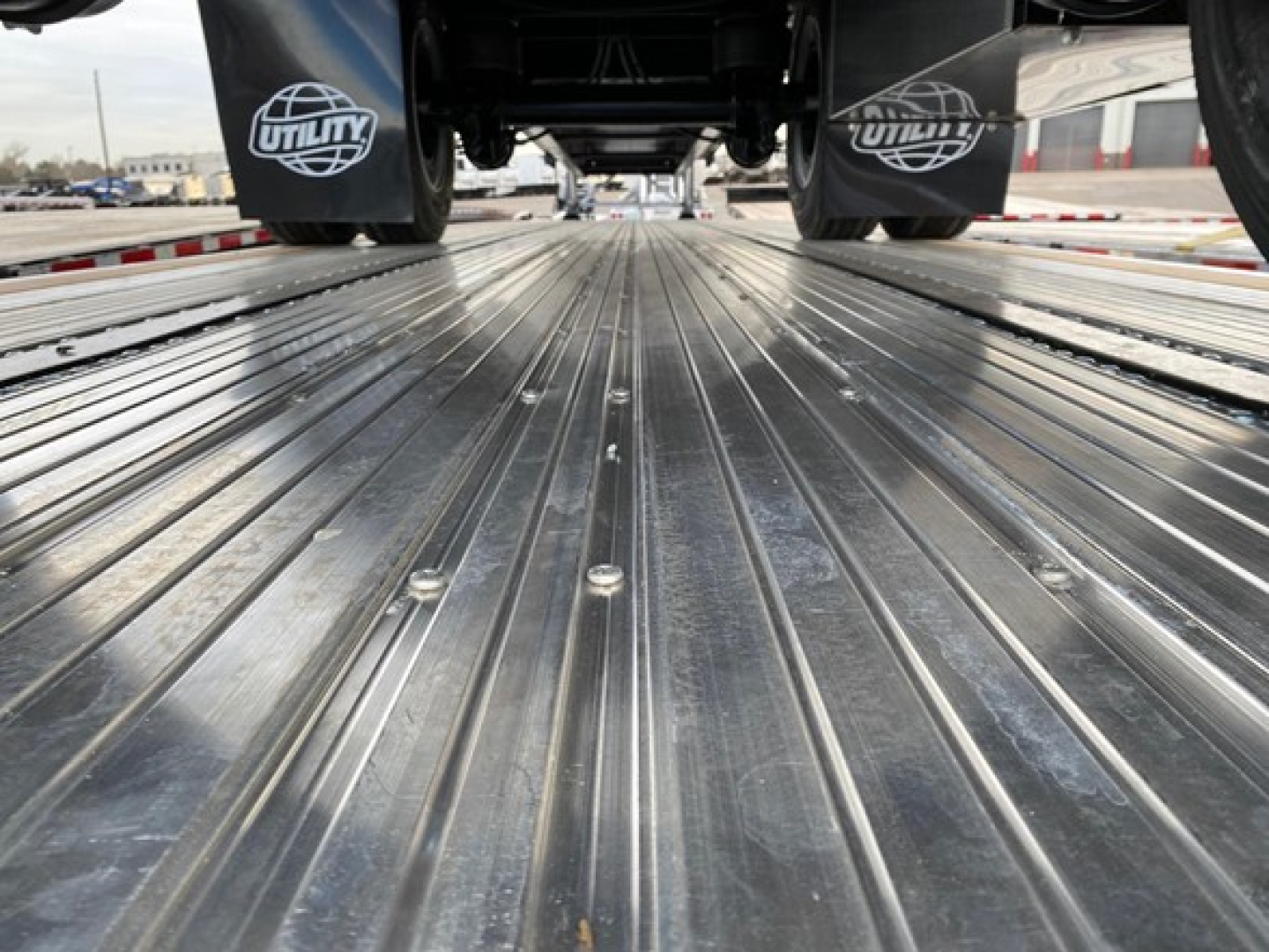 Utility 4000Ae trailer interior showing ribbed metal flatbed surface and undercarriage wheels with Utility branding on mud flaps.