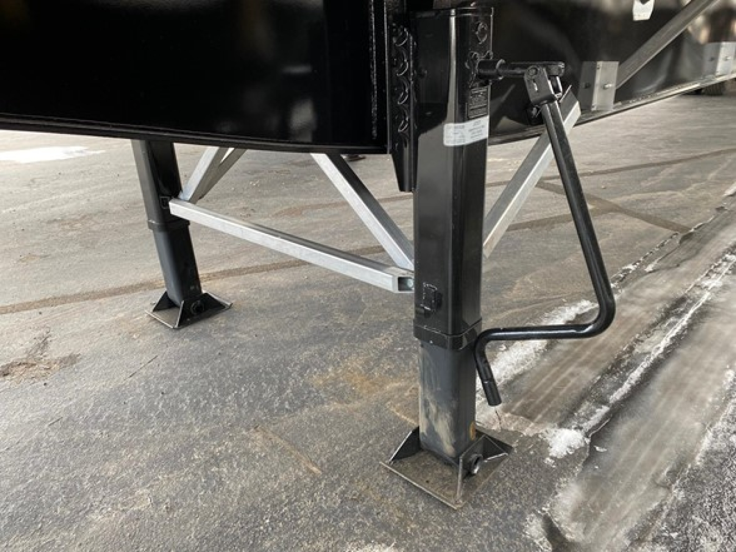 Trailer landing gear and frame leg with footplate and support braces of a Utility 4000Ae flatbed trailer showing steel components and side handle.