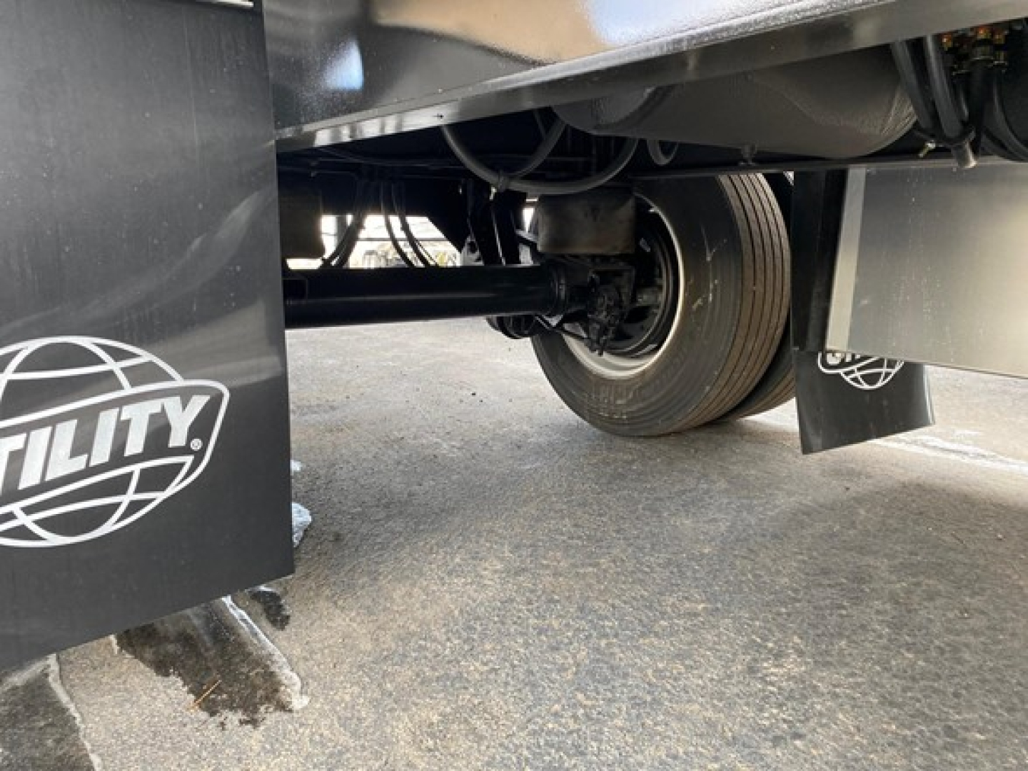Underbelly of Utility 4000Ae trailer showing wheel and suspension, with mudflap labeled 'UTILITY' and various undercarriage components visible.