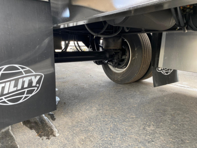 Trailer axle and suspension view showing wheel, leaf springs, and undercarriage of a Utility flatbed trailer.