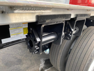 Trailer undercarriage showing tandem axle and mounting hardware for a Utility 4000Ae flatbed trailer; visible components include coupling hardware and wheel assemblies.