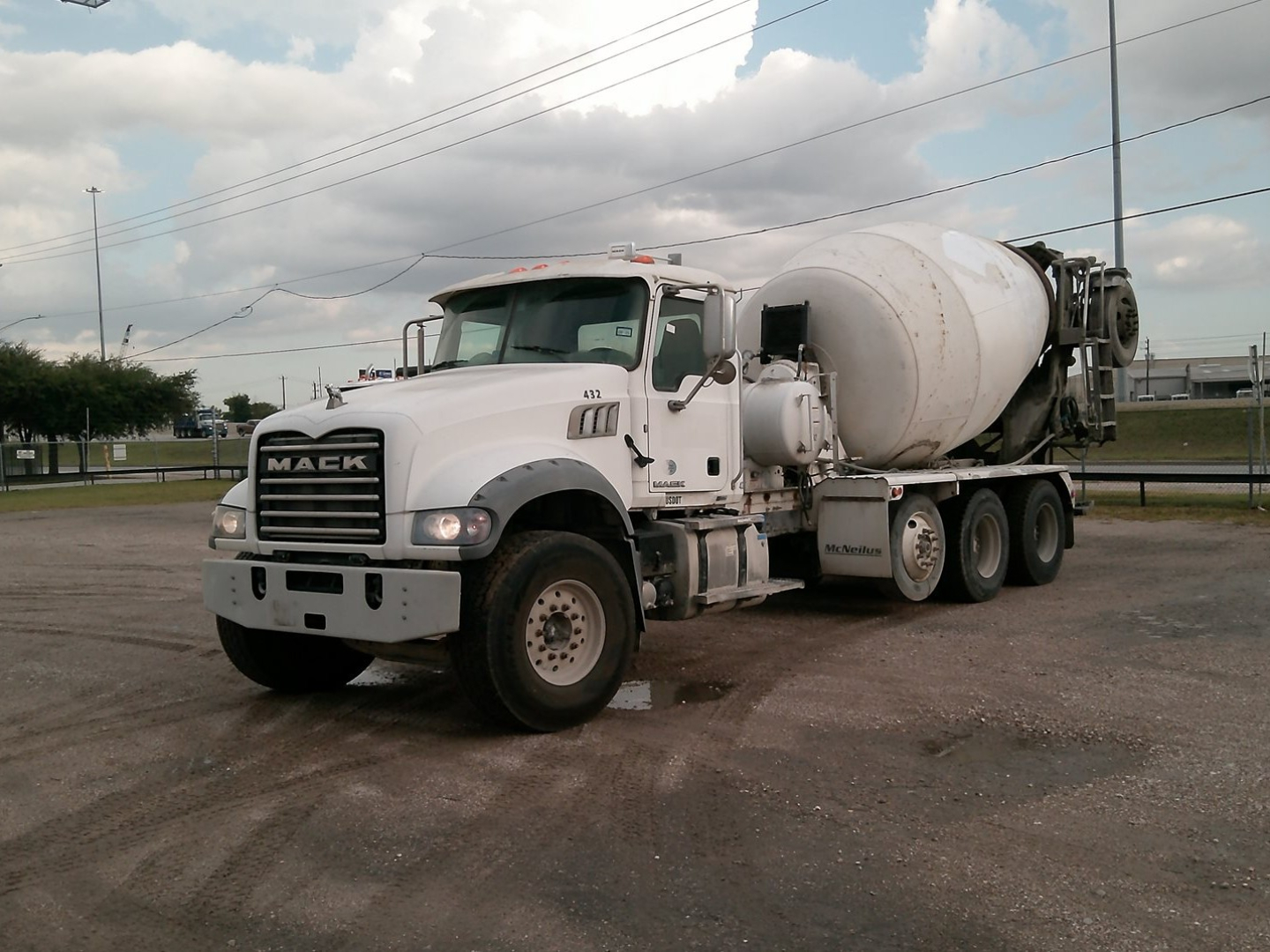 Concrete mixer truck front-left view showing Mack GU713 mixer with白 cement drum and cab, white color, in-service condition.