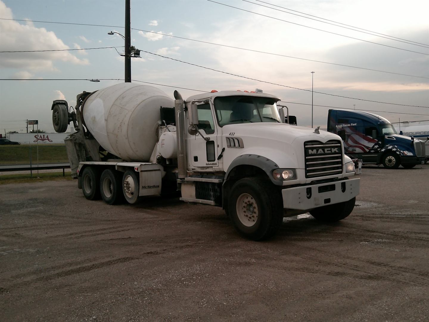 Mixer truck in service with concrete mixer on a Mack GU713 chassis, front view showing cement drum and cab details.
