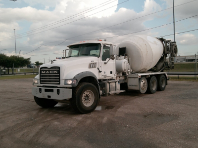 Concrete mixer truck front-left view showing Mack GU713 mixer with白 cement drum and cab, white color, in-service condition.