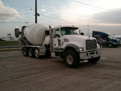 Mixer truck in service with concrete mixer on a Mack GU713 chassis, front view showing cement drum and cab details.