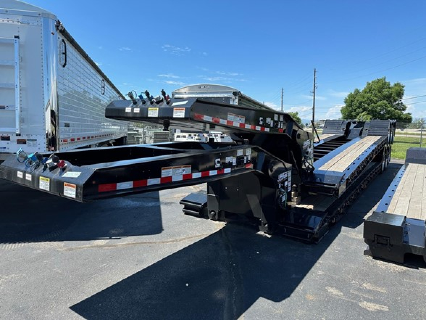 Load King 503-554-SS-SF lowboy trailer in a yard showing gooseneck and long flatbed sections with side rails and hydraulic components.