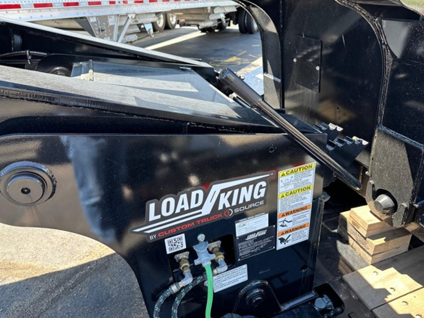 Load King trailer side panel showing Load King logo and warning labels with hoses and fittings.