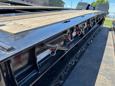 Load King 503-554-SS-SF lowboy trailer side deck showing tie-down rings and metal framework with wooden deck surface.