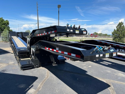 Lowboy trailer with extendable sections and hydraulic ramps, black with safety stripes, exterior view showing frame and support legs.