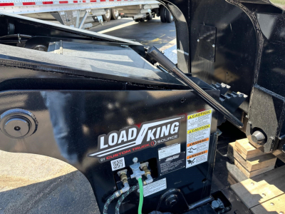 Load King trailer side with labels and hoses visible showing CAUTION and instruction stickers.