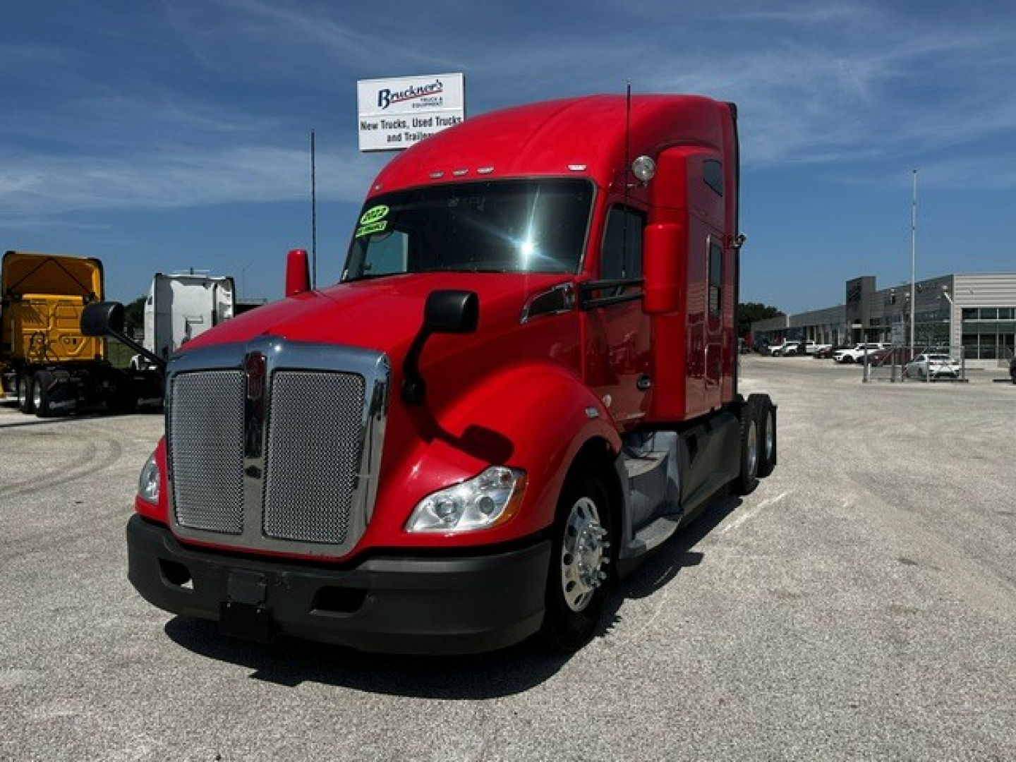 Kenworth T680 sleeper cab tractor in red, front-left angle, showing chrome grille, headlights, and large side mirrors.